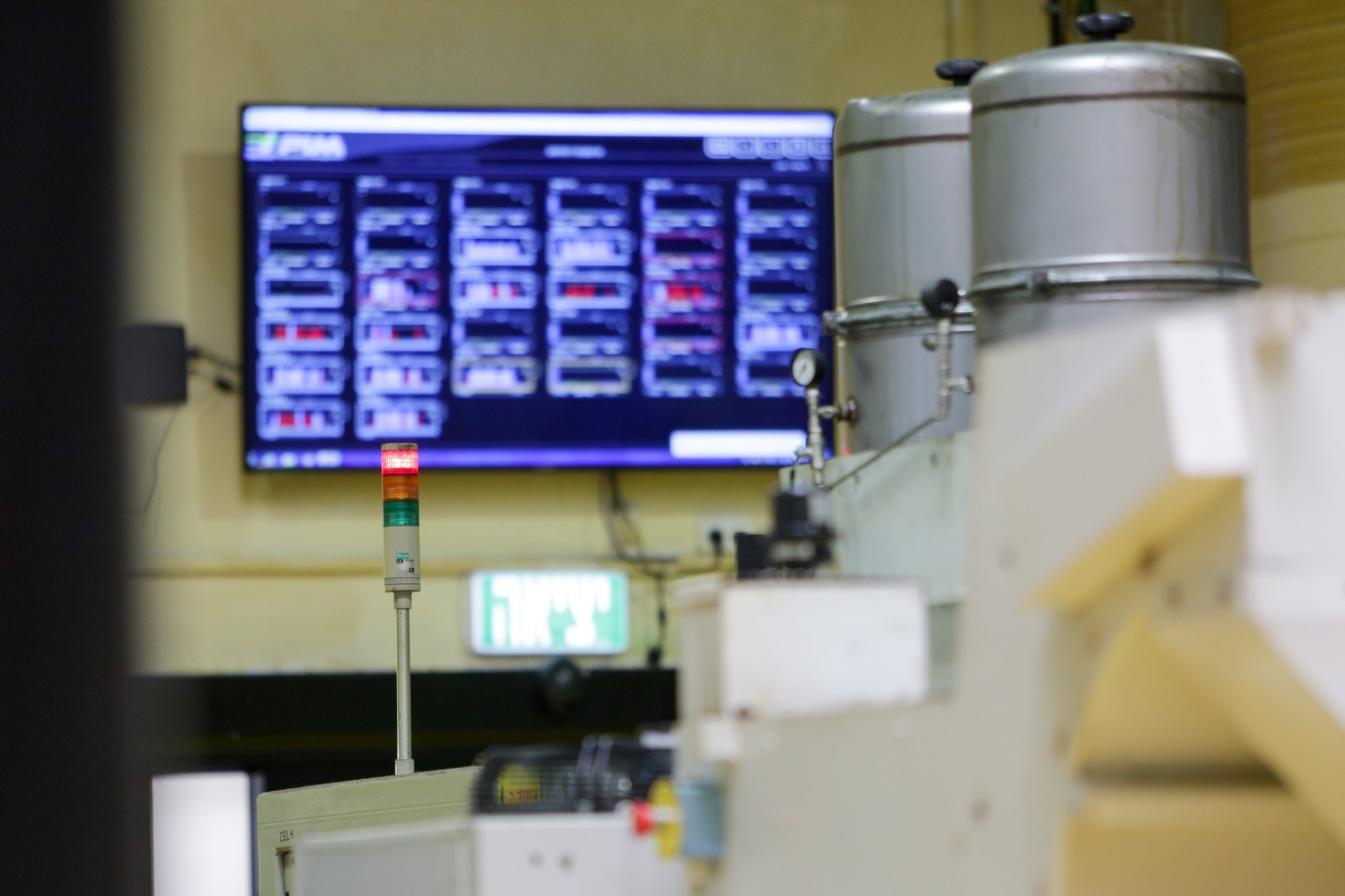 Visual Factories live machine-status screen beside a CNC