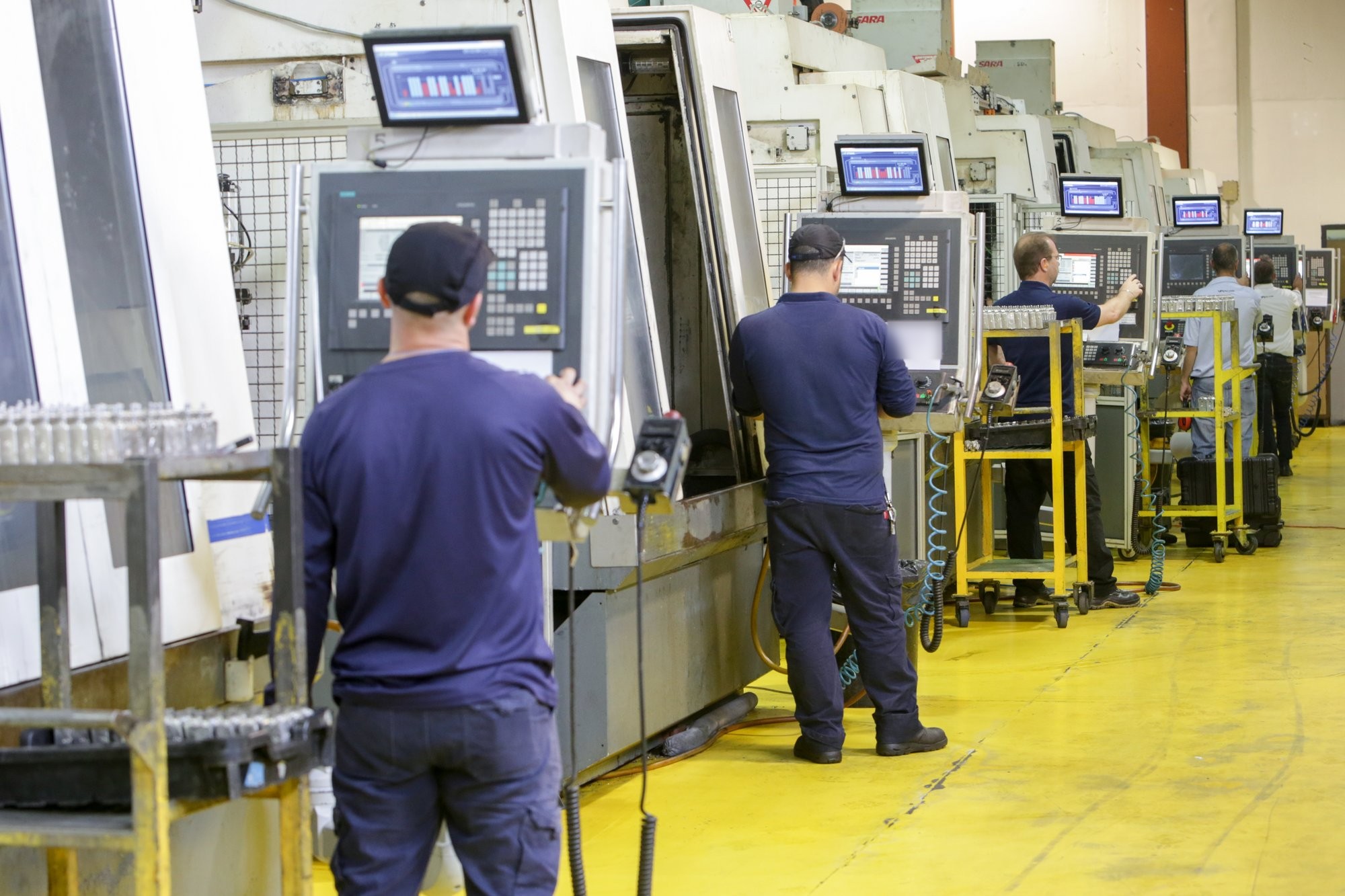 Operadores en tornos CNC con monitores de Visual Factories arriba