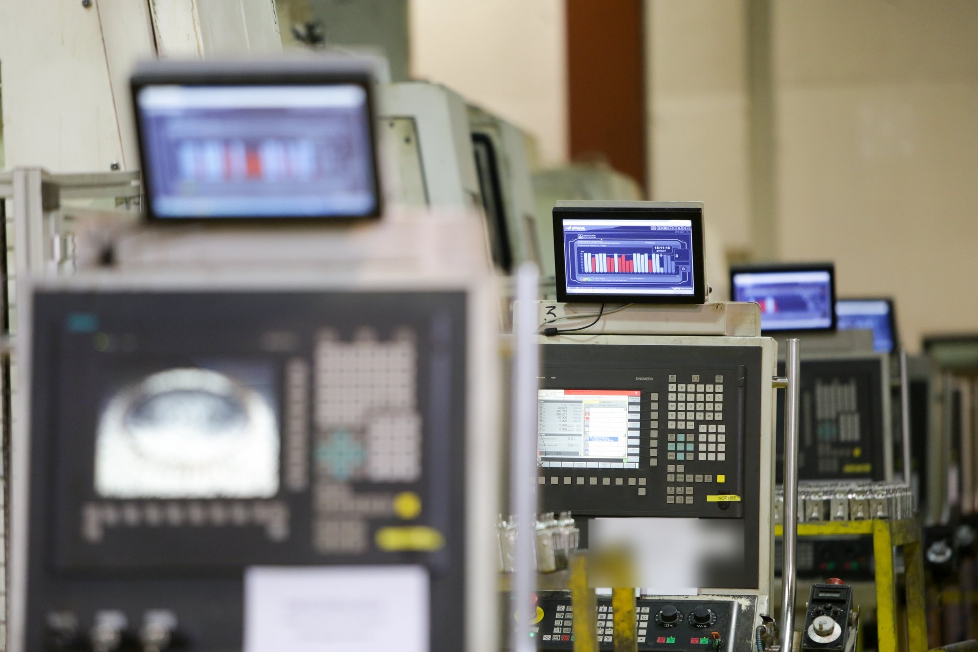 Row of CNC controls on the shop floor